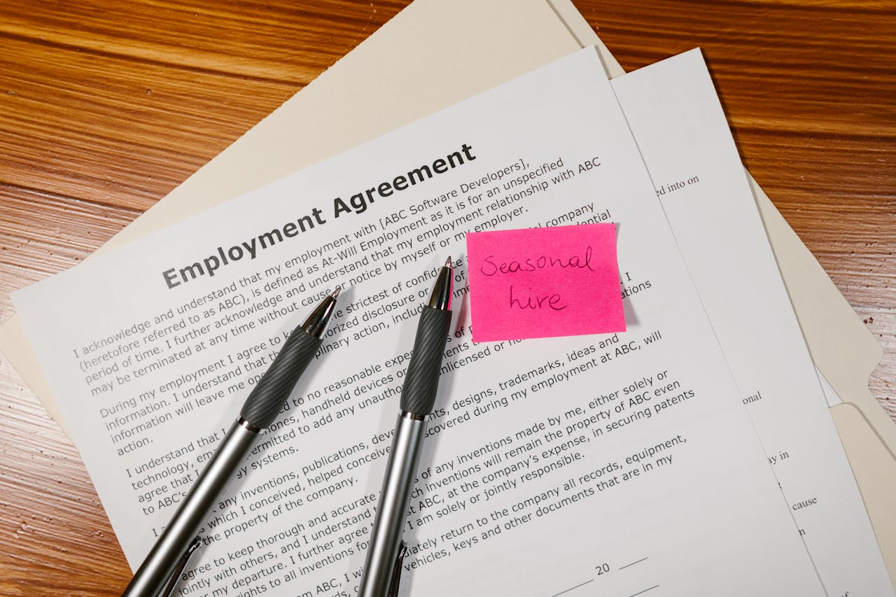 who-we-are Top view of employment agreement contract with pens and seasonal hire note on wooden desk.